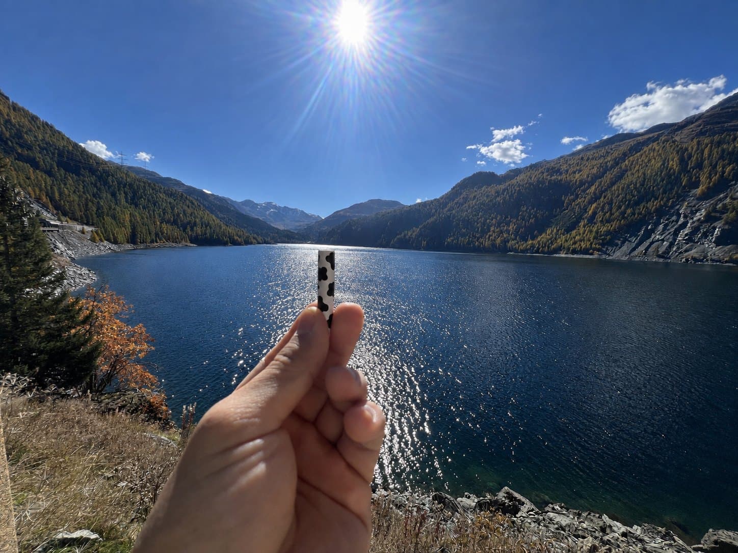 A Hazy Cow filter held up against a mountain reservoir in Switzerland